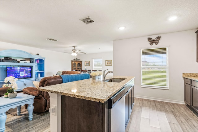 kitchen featuring light wood-type flooring, sink, ceiling fan, a kitchen island with sink, and stainless steel dishwasher