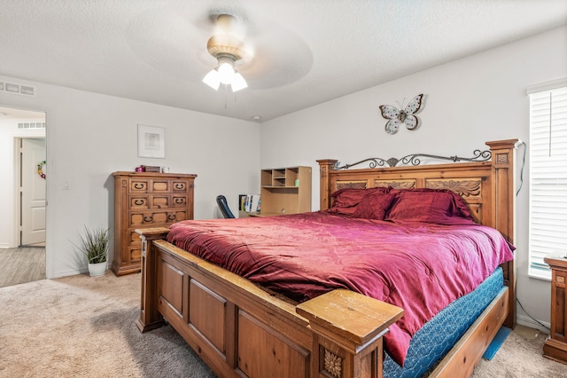 bedroom featuring a textured ceiling, ceiling fan, and light carpet