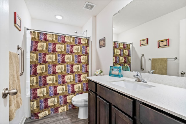 full bathroom featuring toilet, hardwood / wood-style floors, vanity, a textured ceiling, and shower / bath combo