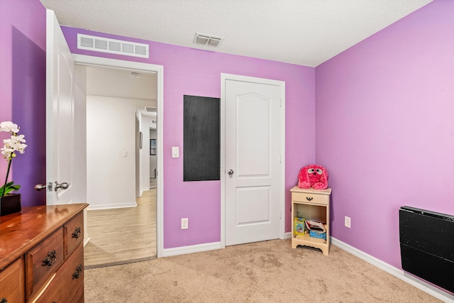 bedroom with light carpet and a textured ceiling