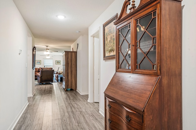 hall with a textured ceiling and light hardwood / wood-style flooring