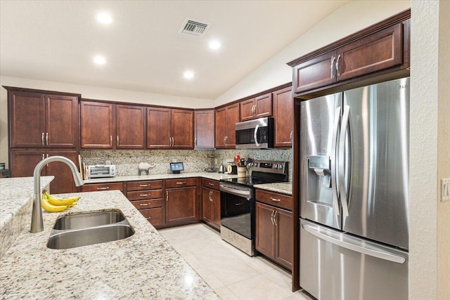 kitchen featuring backsplash, appliances with stainless steel finishes, light stone countertops, sink, and lofted ceiling