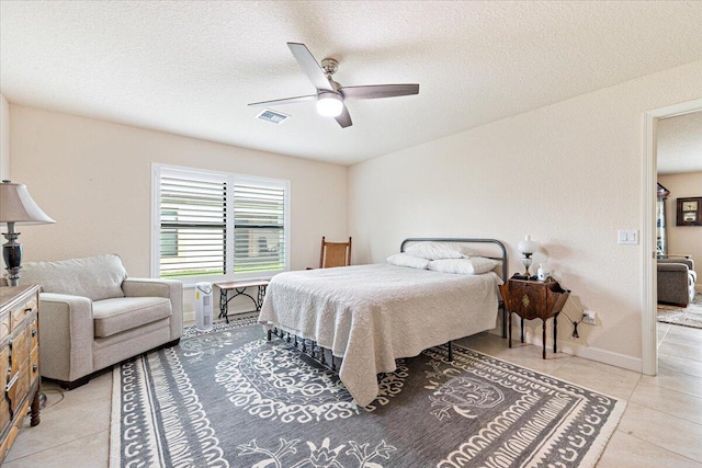 bedroom featuring ceiling fan, light tile patterned floors, and a textured ceiling