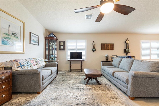 living room featuring ceiling fan and a textured ceiling