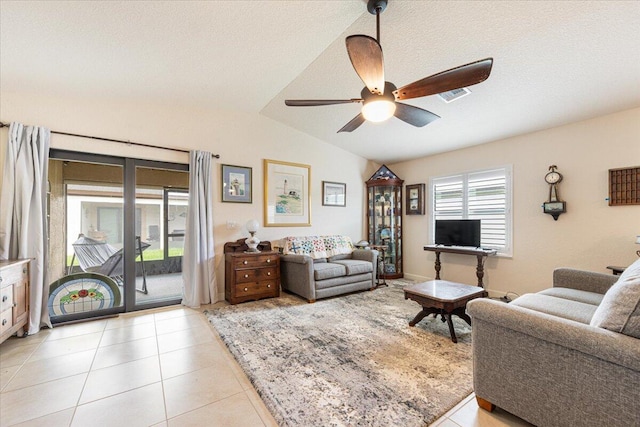 living room featuring a textured ceiling, ceiling fan, light tile patterned floors, and vaulted ceiling