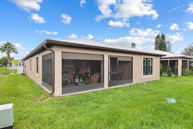 rear view of property with a sunroom and a yard