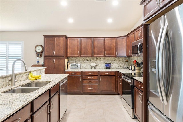 kitchen with tasteful backsplash, light stone countertops, stainless steel appliances, and sink