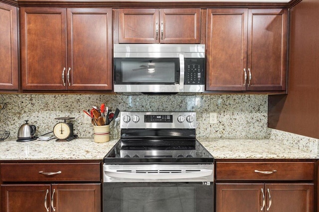 kitchen with backsplash, light stone counters, and stainless steel appliances