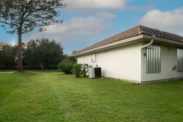 view of home's exterior with cooling unit and a yard