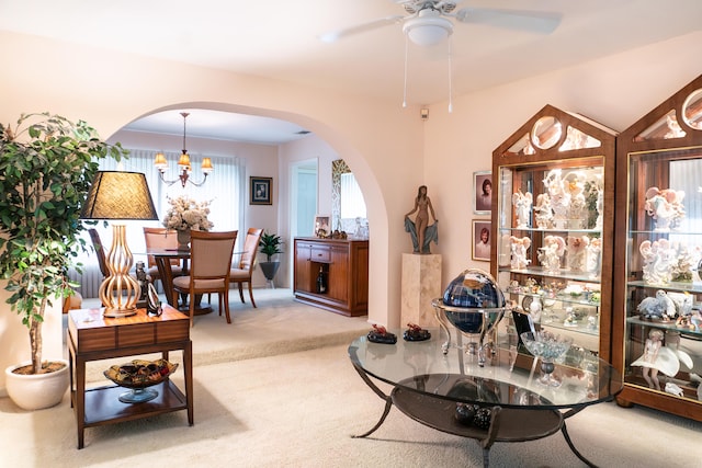 interior space featuring ceiling fan with notable chandelier and light carpet