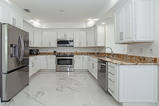 kitchen featuring white cabinetry, stainless steel appliances, light stone countertops, and sink