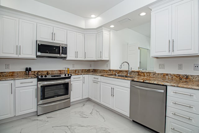 kitchen with sink, stainless steel appliances, dark stone counters, and white cabinets