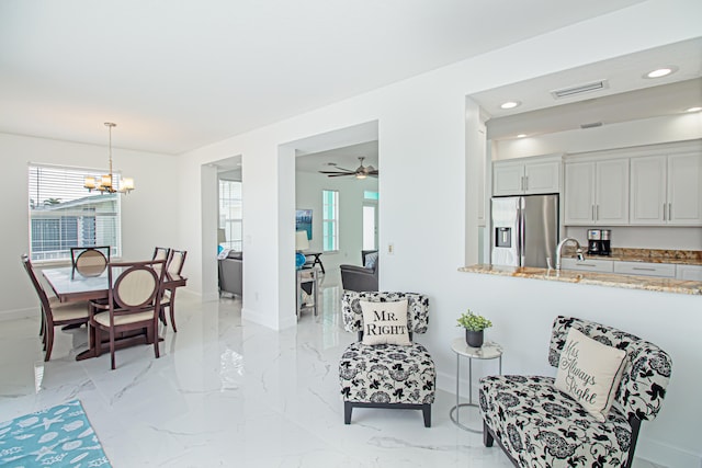 living room featuring sink and ceiling fan with notable chandelier