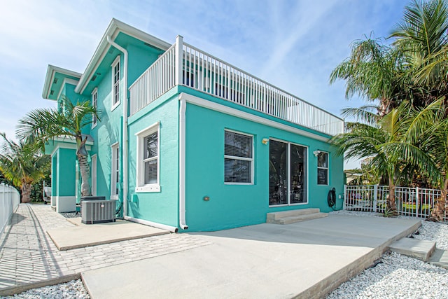 rear view of property with a balcony, cooling unit, and a patio area