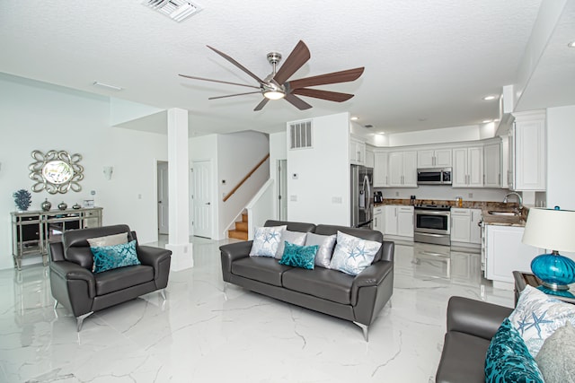 living room with sink, a textured ceiling, and ceiling fan