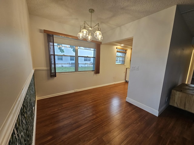 unfurnished dining area with dark hardwood / wood-style floors, an inviting chandelier, and a textured ceiling