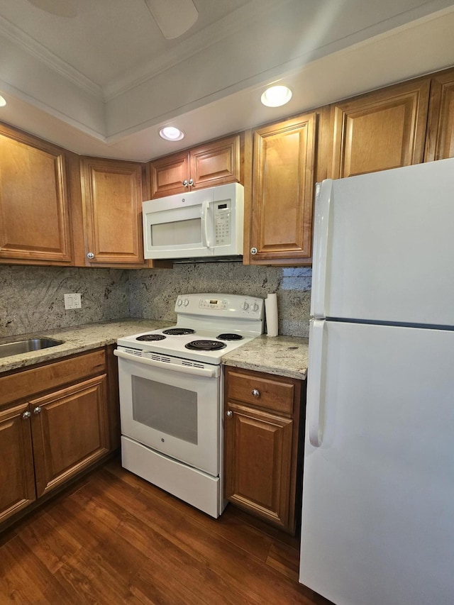 kitchen featuring ornamental molding, white appliances, light stone counters, and dark hardwood / wood-style floors