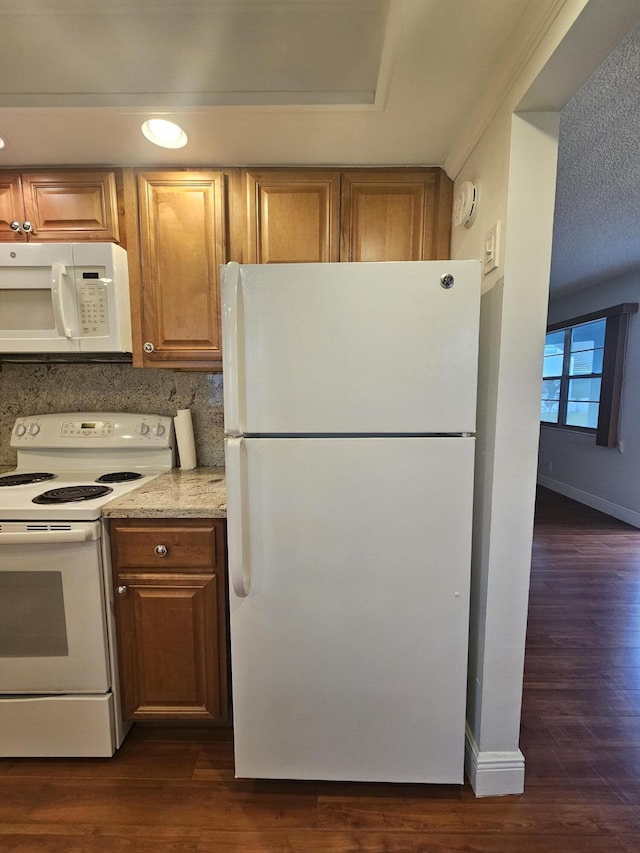 kitchen with white appliances, dark hardwood / wood-style flooring, and a textured ceiling