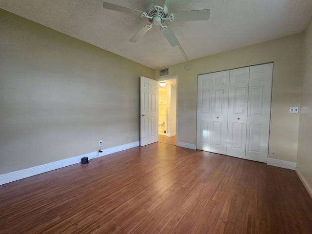 unfurnished bedroom featuring a textured ceiling, wood-type flooring, ceiling fan, and a closet