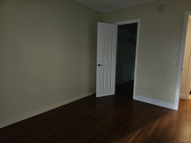 36 Islewood B, Deerfield Beach, FL 33442 - unfurnished bedroom with dark wood-type flooring, baseboards, a closet, a textured ceiling, and a walk in closet