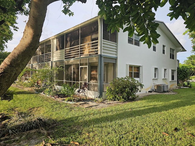 36 Islewood B, Deerfield Beach, FL 33442 - rear view of property featuring a sunroom, a yard, central air condition unit, and stucco siding