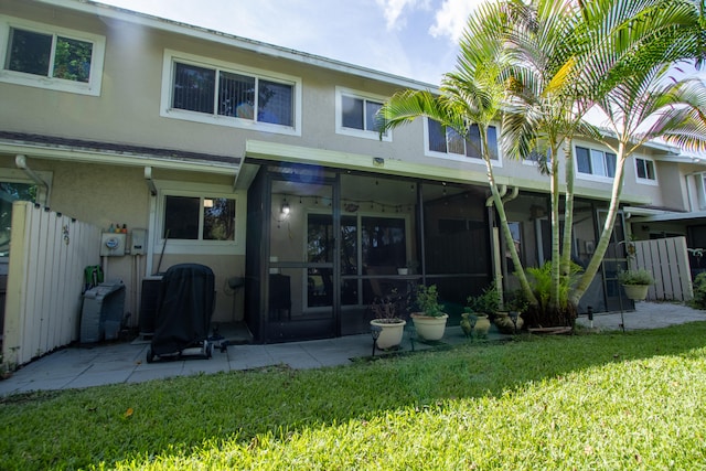 rear view of property with a patio area, a yard, and a sunroom