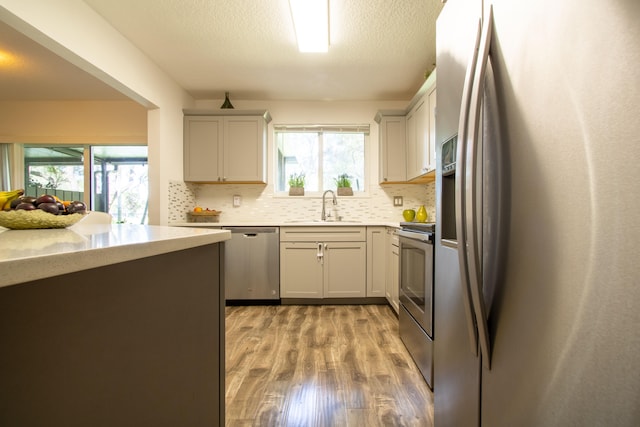 kitchen featuring gray cabinetry, light hardwood / wood-style flooring, tasteful backsplash, stainless steel appliances, and sink