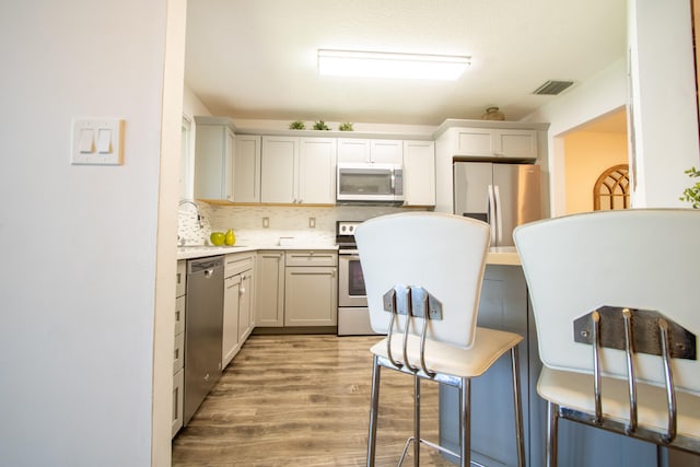 kitchen featuring light hardwood / wood-style flooring, stainless steel appliances, sink, and backsplash