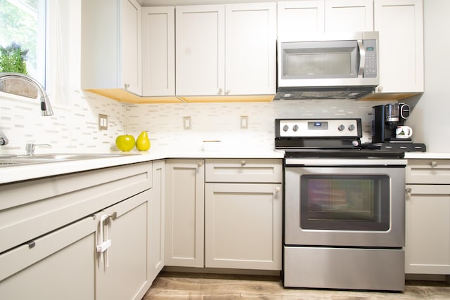 kitchen featuring light wood-type flooring, white cabinetry, tasteful backsplash, stainless steel appliances, and sink