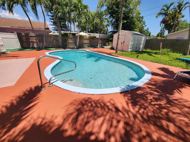 view of swimming pool with a shed, a patio, an outdoor structure, and a fenced backyard