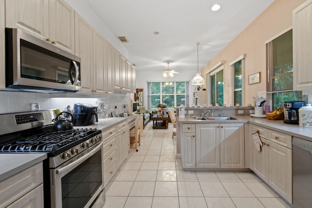 kitchen with decorative light fixtures, stainless steel appliances, sink, decorative backsplash, and ceiling fan