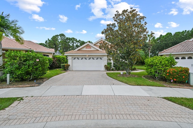 mediterranean / spanish-style home with a tiled roof, decorative driveway, a garage, and stucco siding