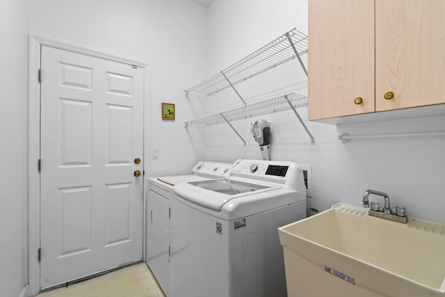 clothes washing area with cabinets, sink, and independent washer and dryer