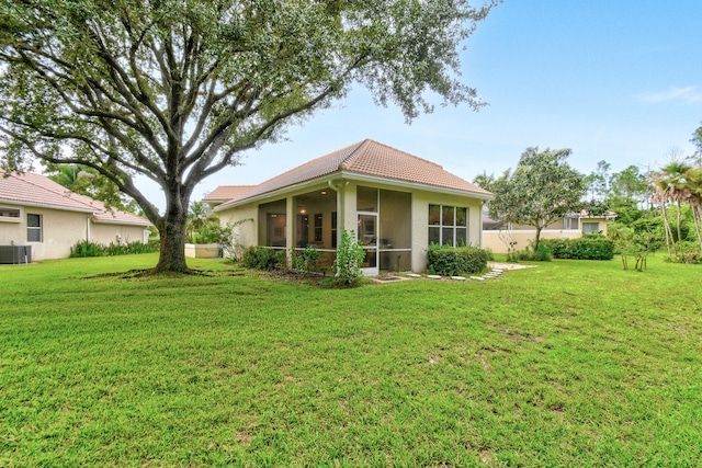 rear view of house with a yard, a sunroom, and central AC unit