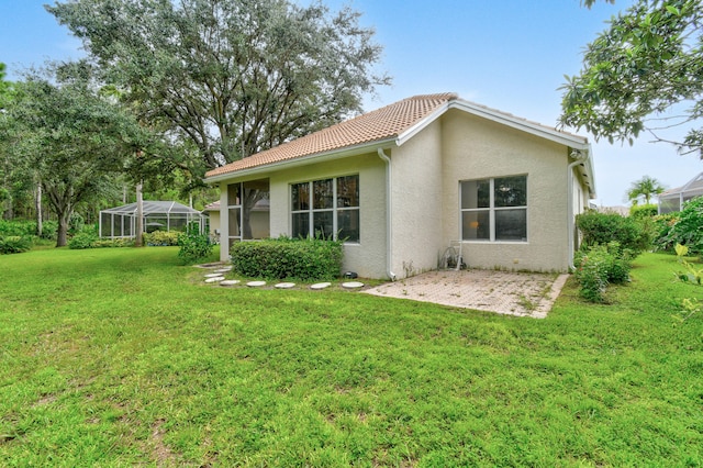 back of property featuring a patio area, a lawn, and a lanai