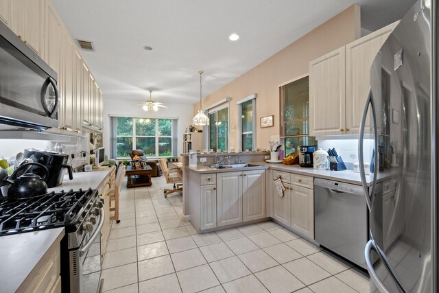 kitchen featuring kitchen peninsula, ceiling fan, hanging light fixtures, appliances with stainless steel finishes, and light tile patterned flooring