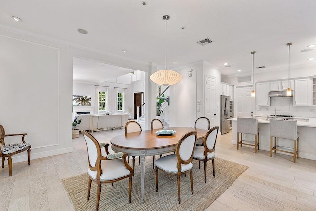 dining room featuring ornamental molding and light hardwood / wood-style flooring