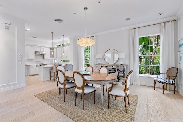 dining room with crown molding and light hardwood / wood-style flooring