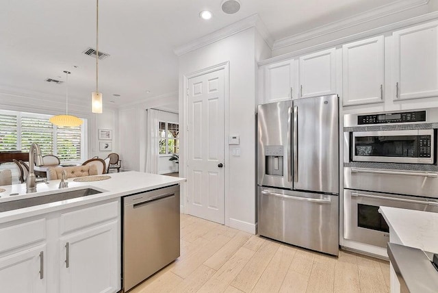 kitchen with pendant lighting, light hardwood / wood-style floors, stainless steel appliances, sink, and white cabinetry