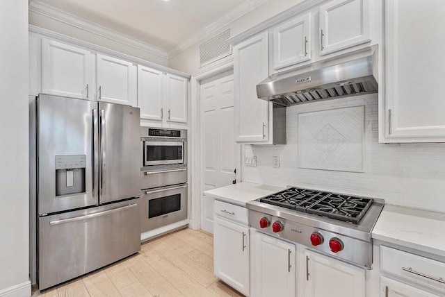 kitchen with light hardwood / wood-style floors, stainless steel appliances, ornamental molding, white cabinetry, and light stone counters