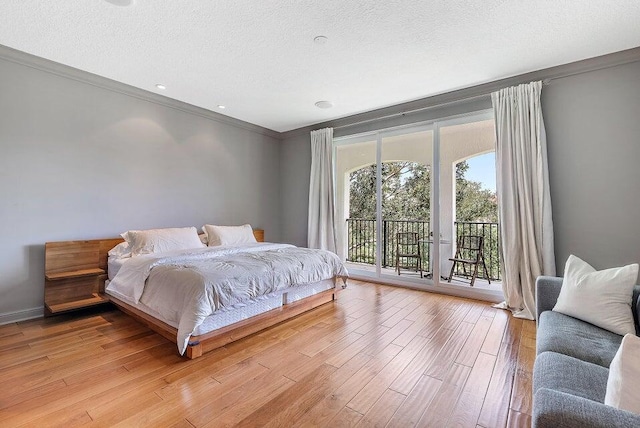 bedroom with crown molding, access to exterior, light wood-type flooring, and a textured ceiling