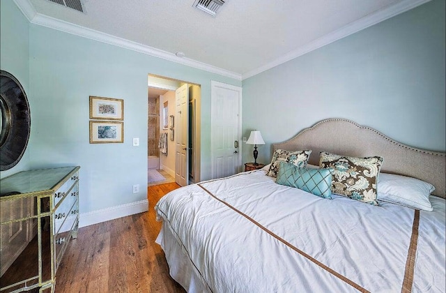 bedroom with crown molding, ensuite bath, and hardwood / wood-style flooring