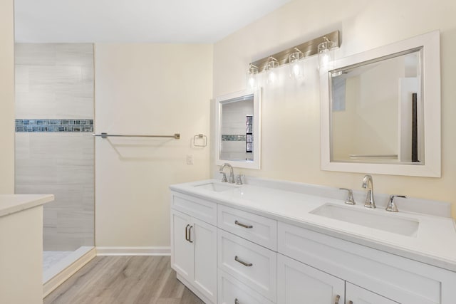 bathroom with tiled shower, vanity, and hardwood / wood-style floors