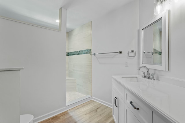 bathroom featuring tiled shower, wood-type flooring, toilet, and vanity