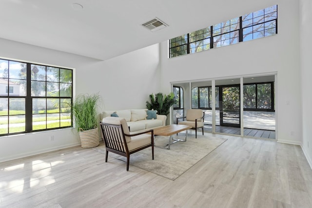 living room featuring a towering ceiling and light wood-type flooring