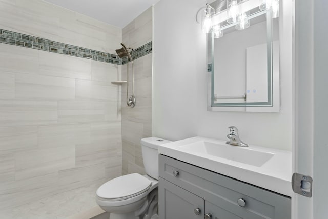 bathroom featuring tiled shower, vanity, and toilet