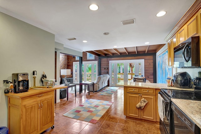 kitchen with kitchen peninsula, french doors, wooden walls, black appliances, and light tile patterned floors