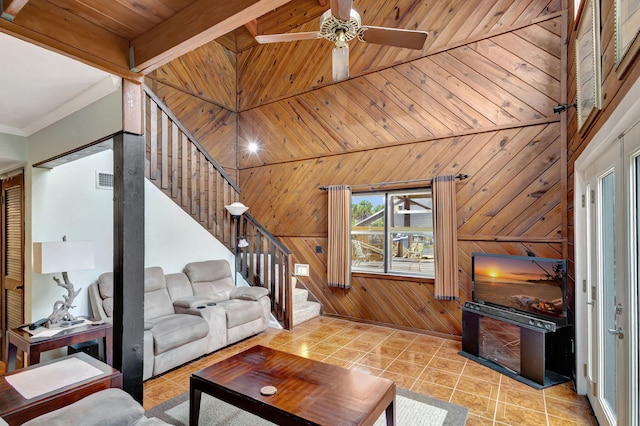 living room featuring wood ceiling, ceiling fan, beam ceiling, wood walls, and light tile patterned flooring