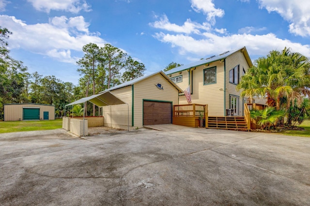 exterior space with a carport, a garage, an outdoor structure, and a wooden deck