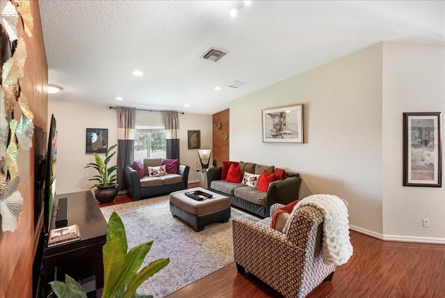 living room with a textured ceiling, hardwood / wood-style floors, and lofted ceiling